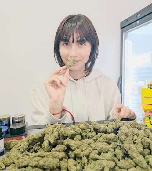 Nerea Banacloy from Linda Seeds with CBD flowers spread out in front of her while smelling a CBD flower she is holding.